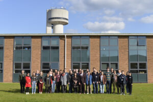 Workshop attendees in front of offices at Daresbury Laboratory; a distinctive white tower is in the background.